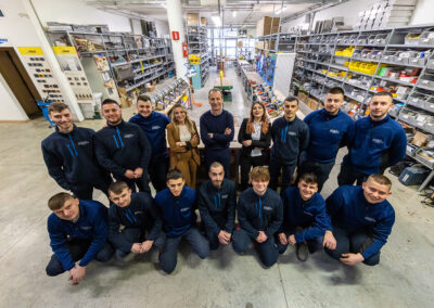 Foto di gruppo aziendale con uomini e donne sorridenti in un magazzino.